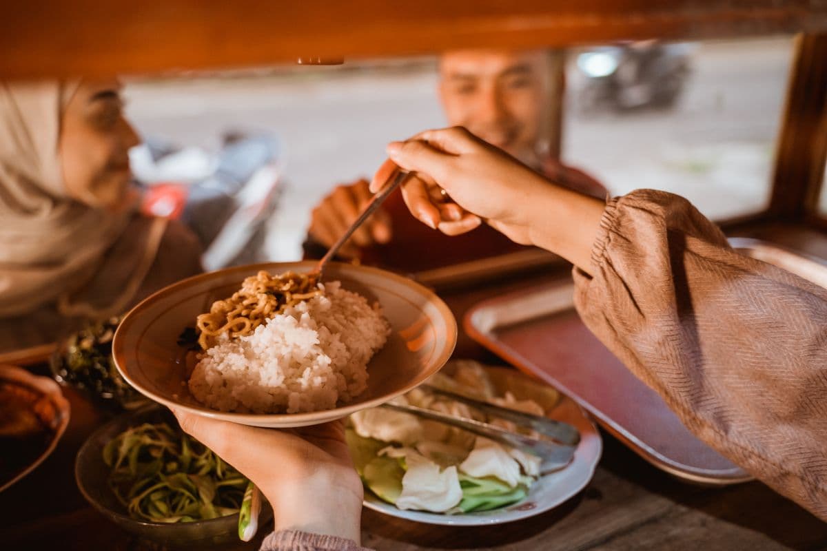 Seorang wanita sedang mengambil makanan di warung