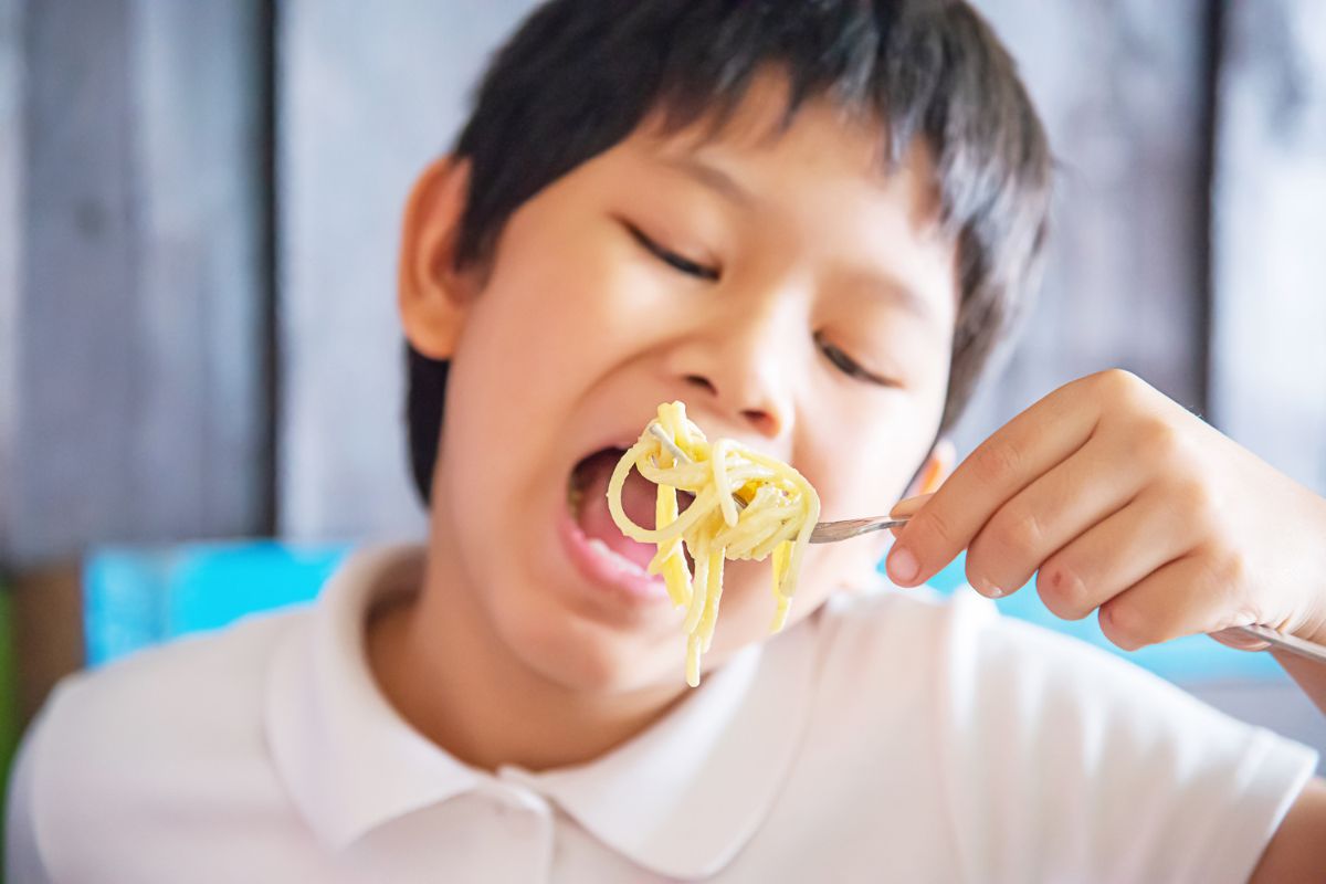 Anak laki-laki sedang makan pasta