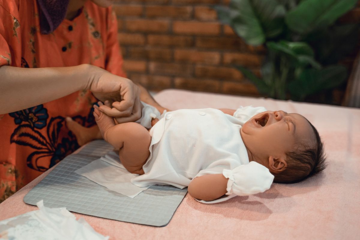 Seorang wanita sedang mengganti popok bayi