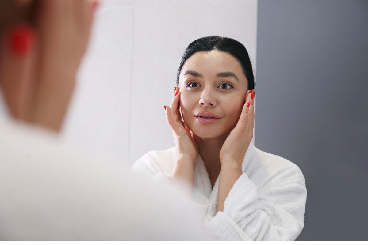 Wanita muda sedang berkaca di cermin kamar mandi