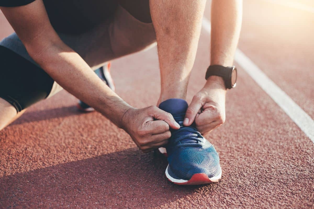 pria sedang mengikat tali sepatu di lapangan lari