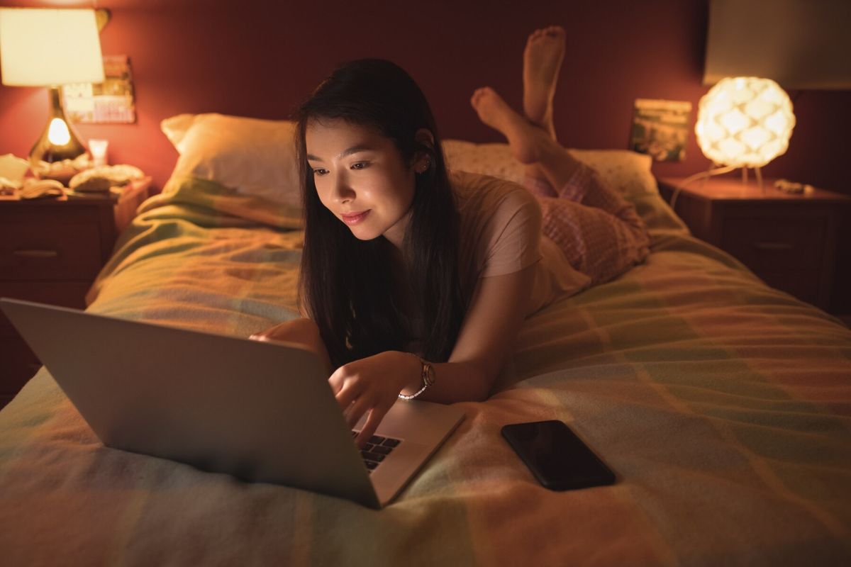 Seorang wanita sedang begadang sambil bermain laptop