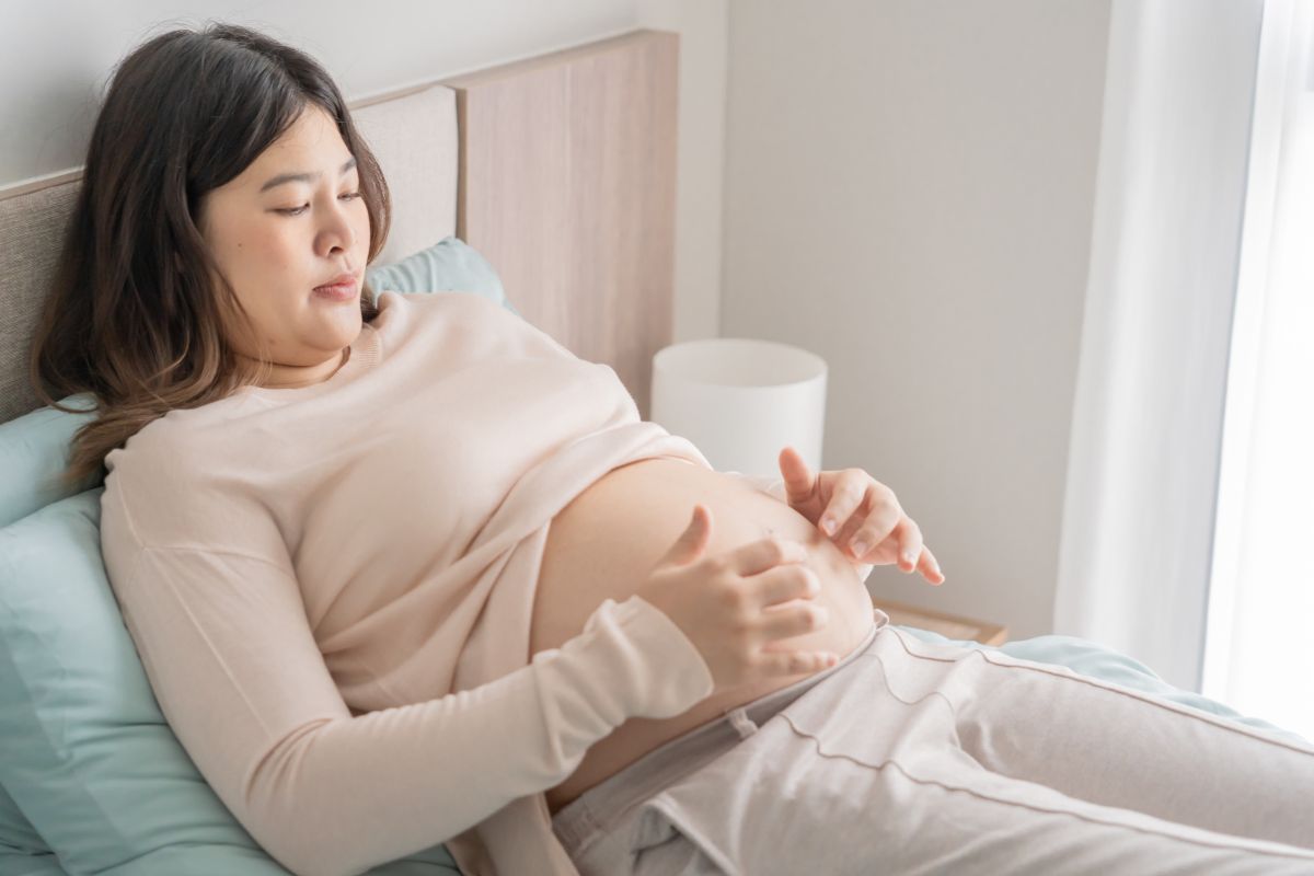 Wanita hamil sedang berbaring di atas tempat tidur