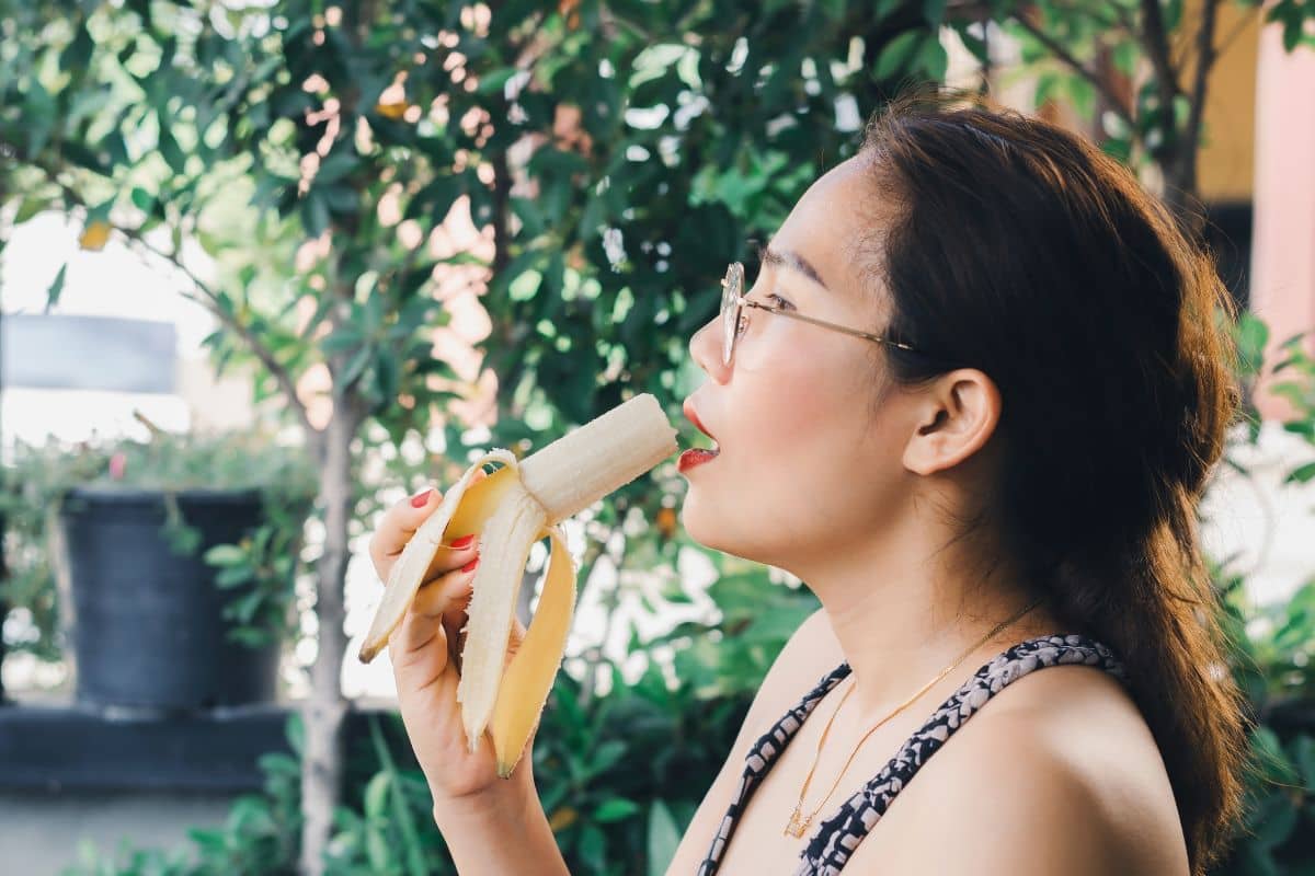 Wanita sedang memakan buah pisang