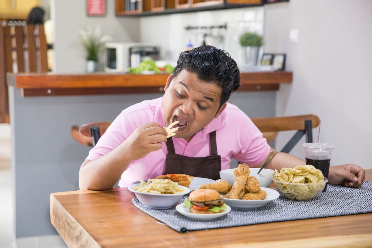 Seorang pria sedang memakan makanan tinggi kolesterol