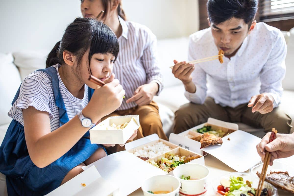 Seorang anak perempuan dan pria sedang menyantap makanan