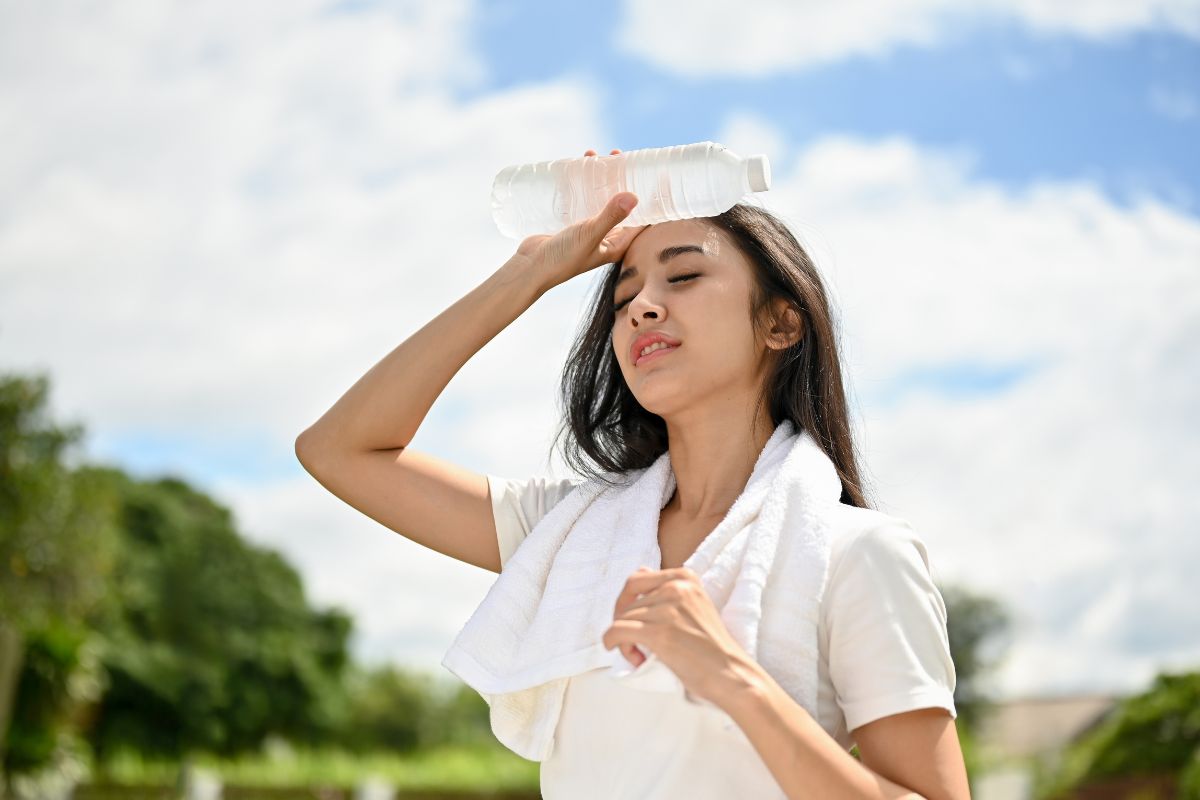 Wanita yang kepanasan sedang membawa botol air mineral