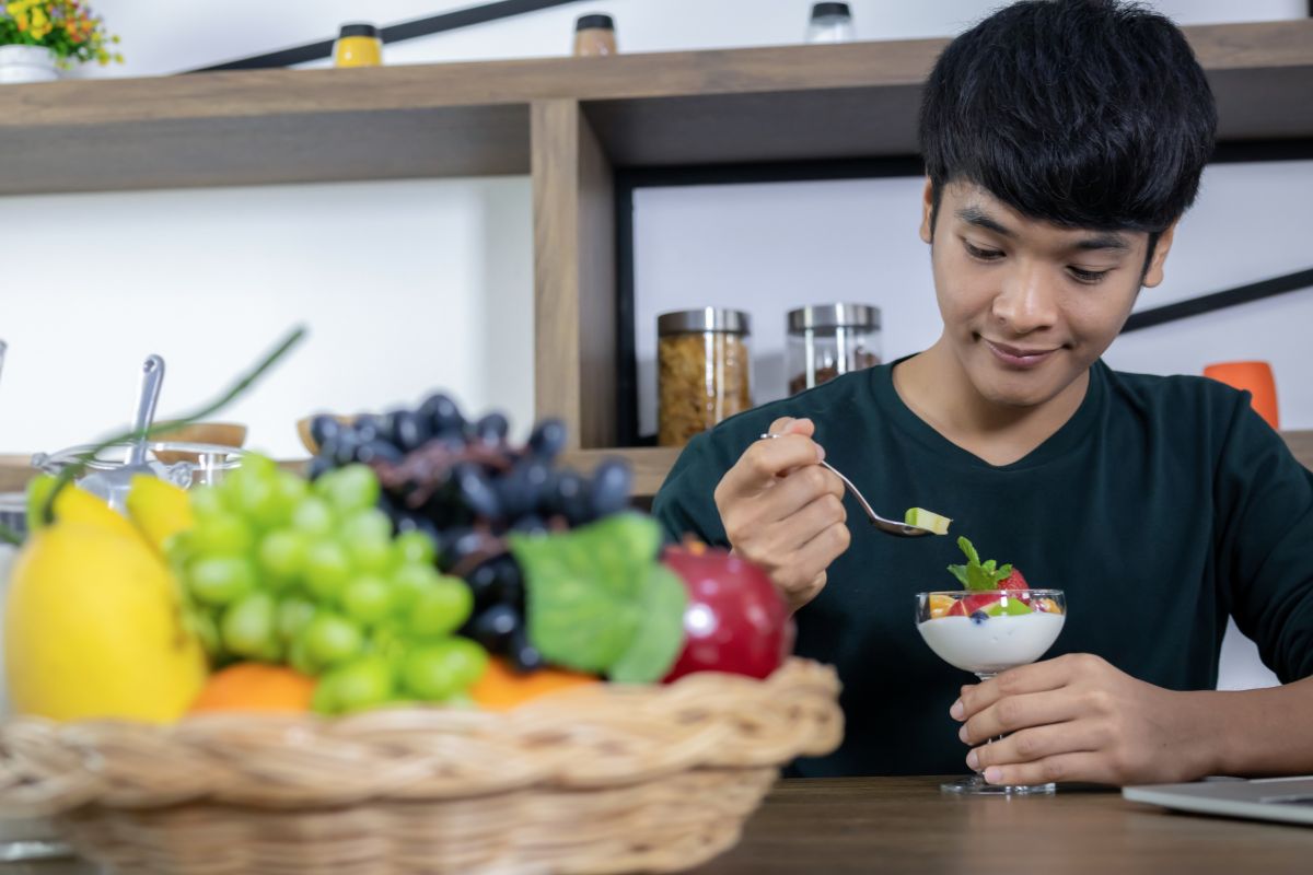 Pria sedang makan yogurt dengan topping buah