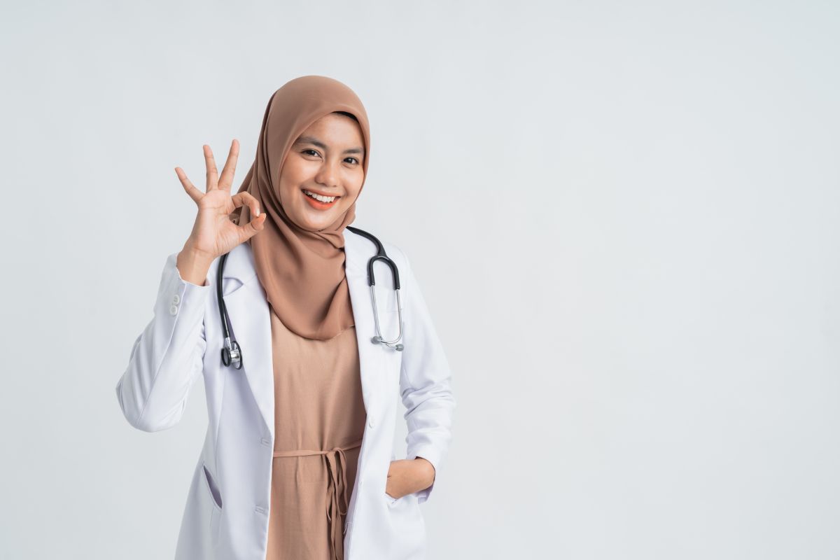 Dokter wanita berjilbab memberi gestur "OK"