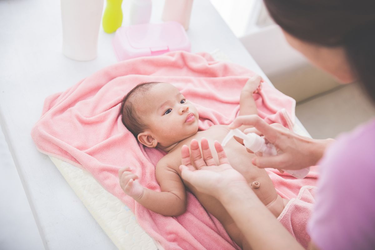 Ibu mengoleskan losion pada kulit bayi