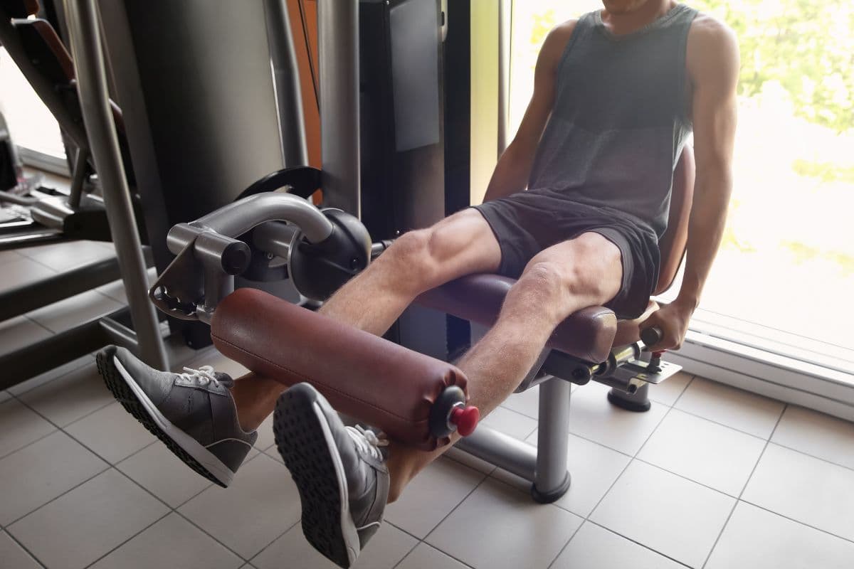 Pria sedang menggunakan alat leg curl