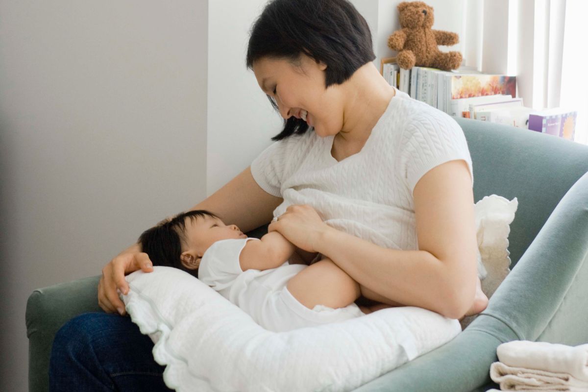 Seorang ibu sedang menyusui dengan menggunakan bantal menyusui