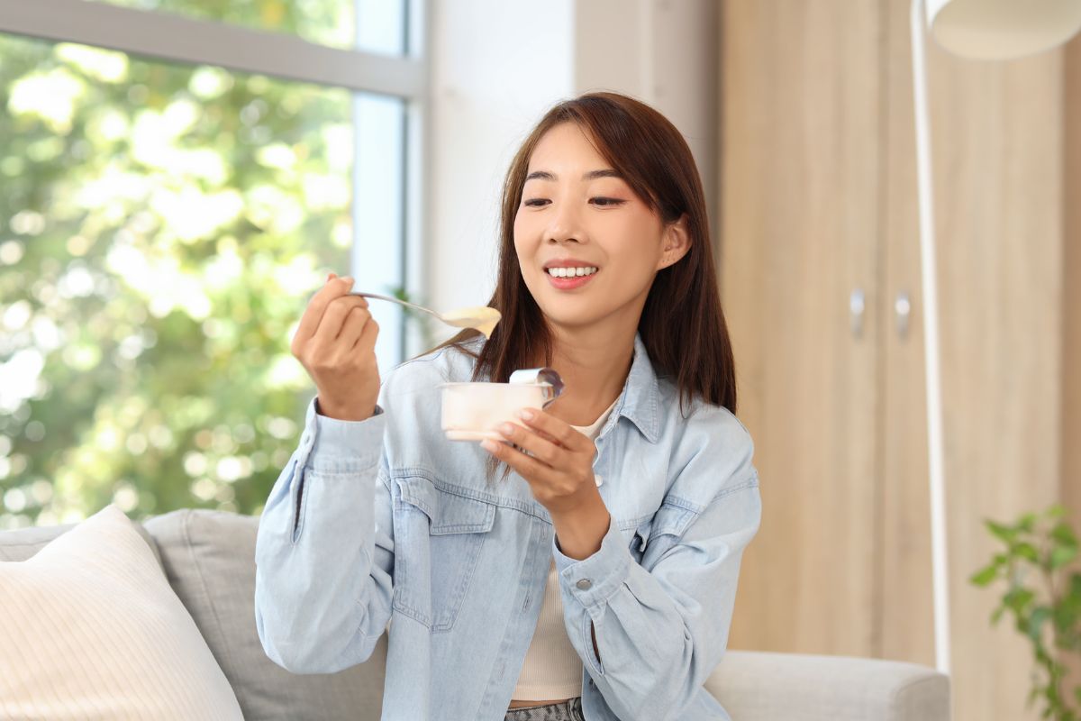 Seorang wanita sedang memakan yogurt