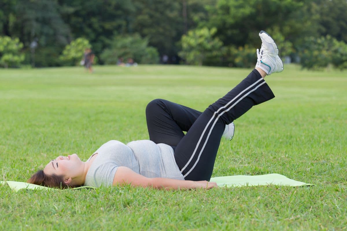 Wanita melakukan bicycle crunches di taman