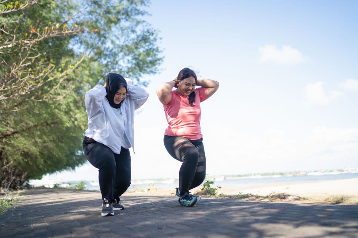 Dua orang wanita melakukan squat jump di pinggir pantai