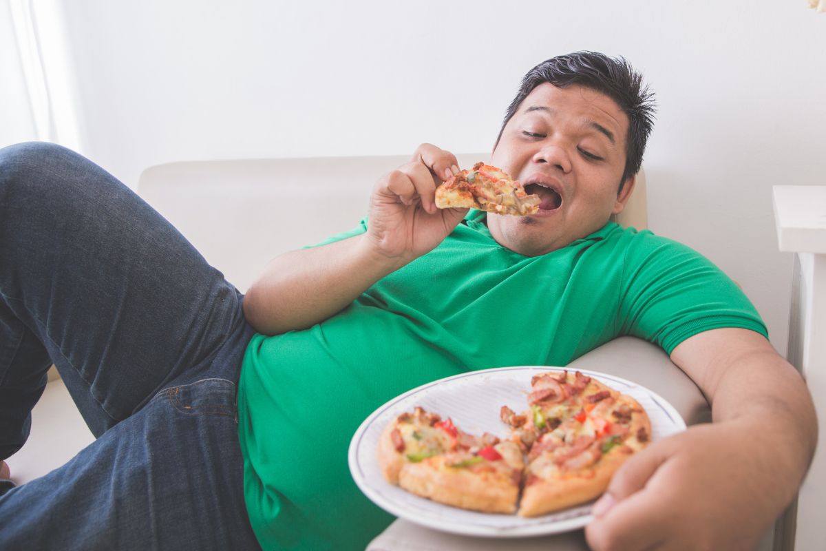 Pria sedang makan pizza sambil bersantai