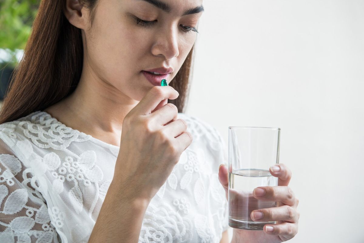 Wanita sedang minum obat