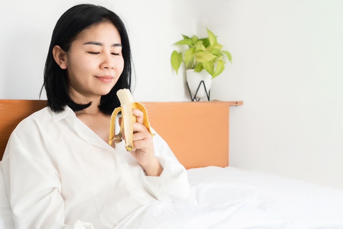 Seorang wanita sedang memakan pisang yang tinggi potasium