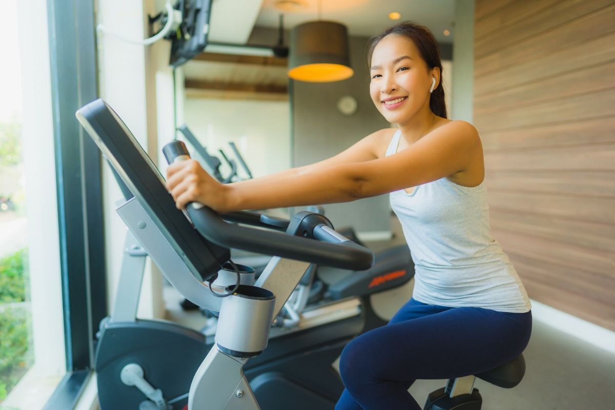 Wanita sedang menggunakan stationary bike di gym