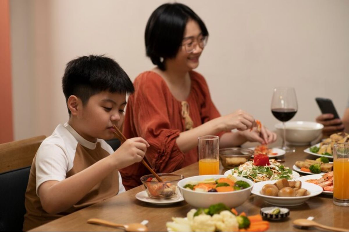 Anak laki-laki dan ibunya sedang makan di meja makan