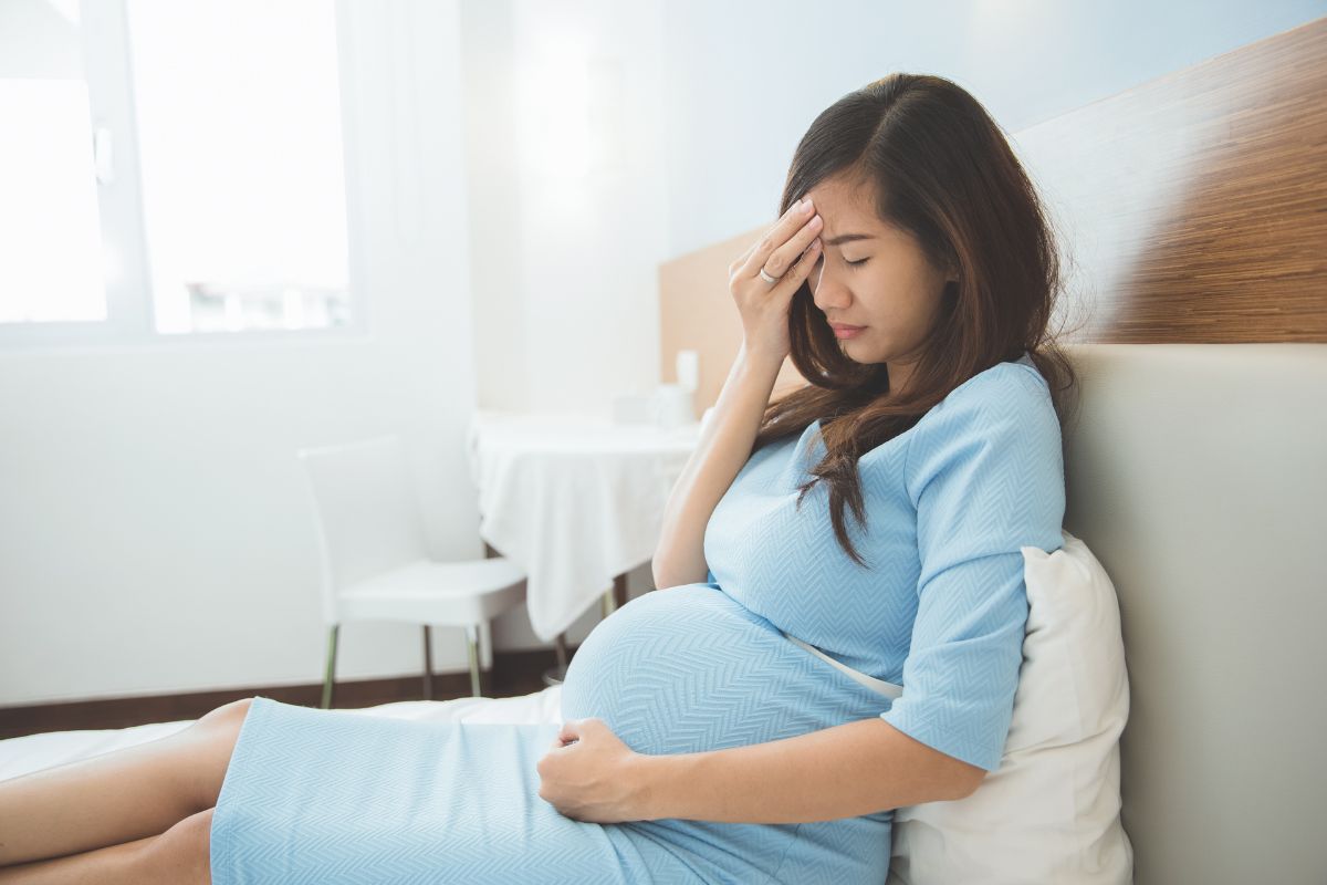 Wanita hamil sedang duduk di atas tempat tidur