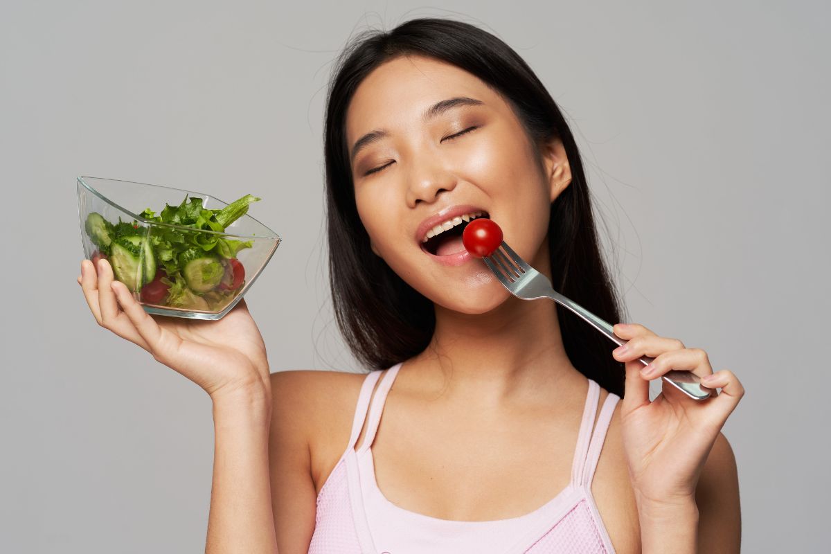 Wanita memakan tomat merah