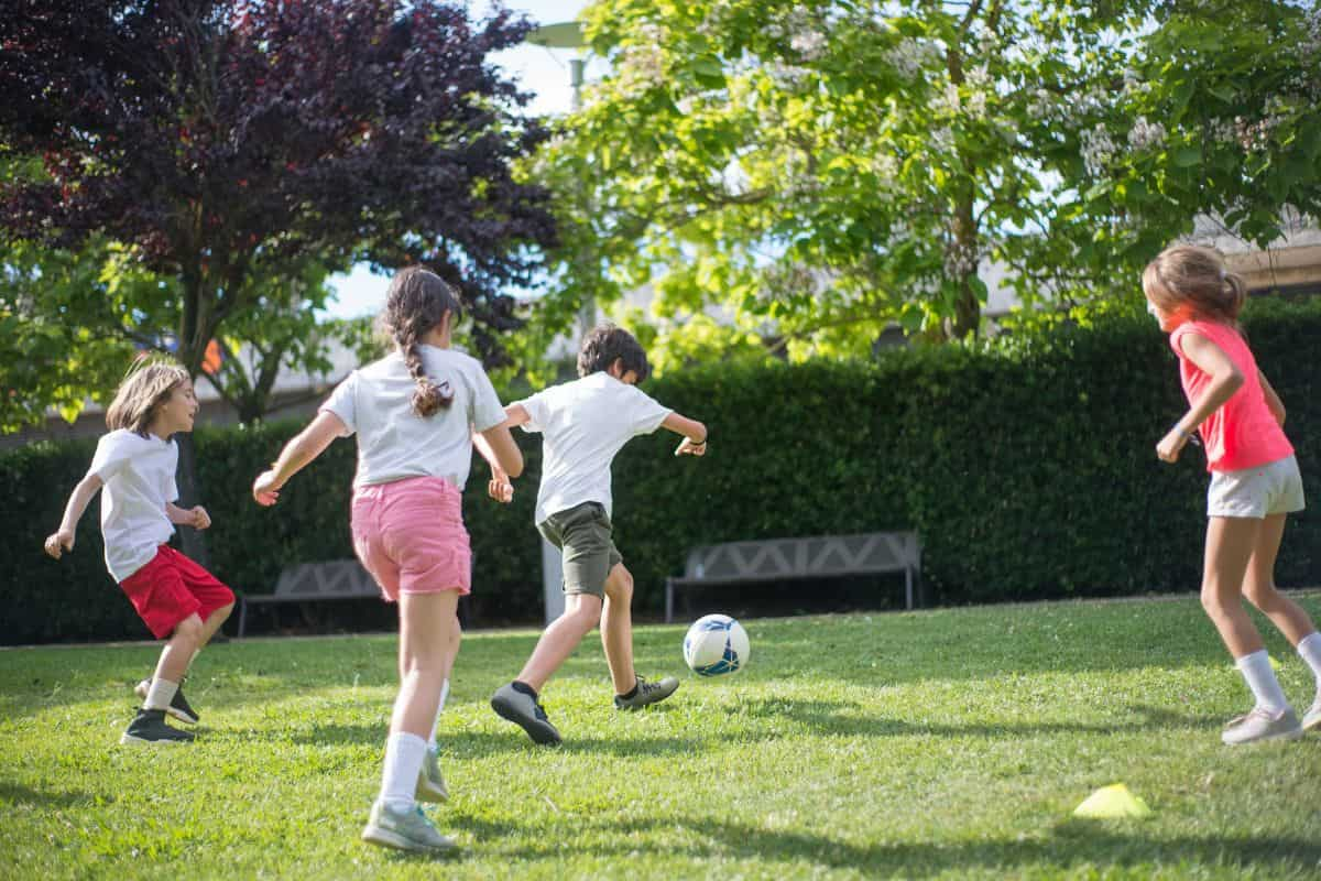 Sekelompok anak sedang bermain sepak bola di lapangan