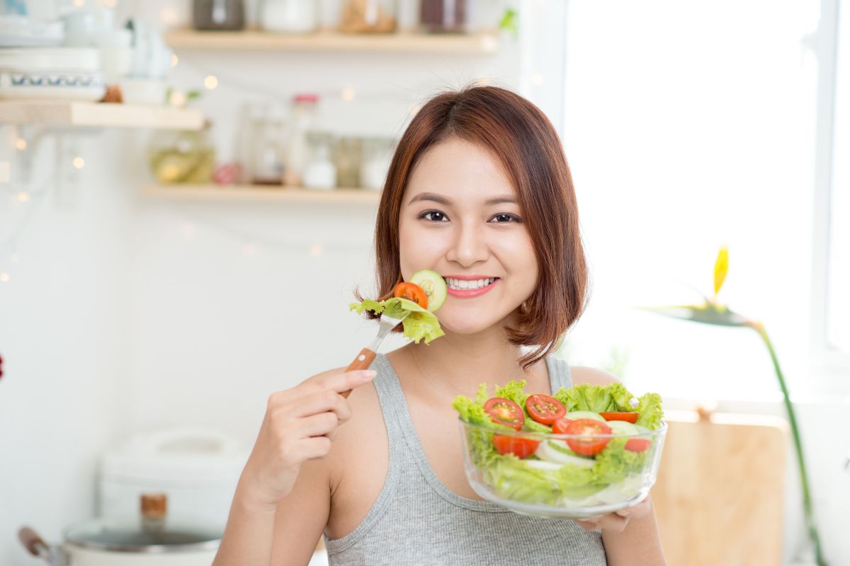 Seorang wanita sedang mengonsumsi makanan sehat