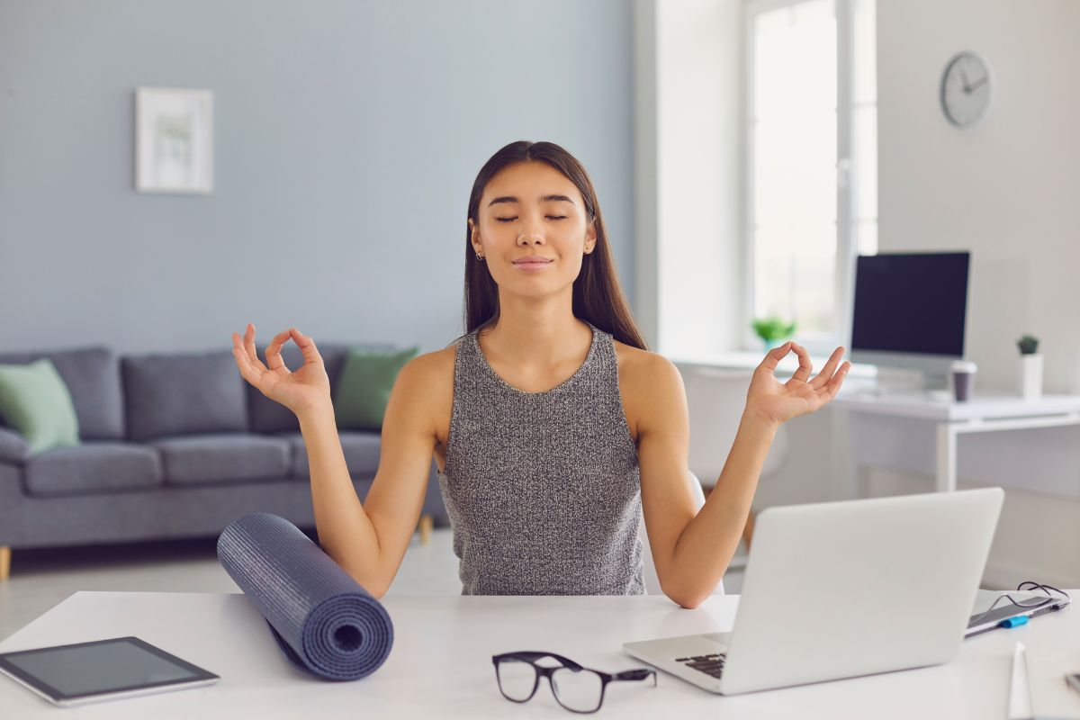 Wanita muda melakukan meditasi di depan laptop