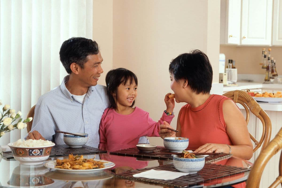 anak yang sedang makan dengan orang tuanya