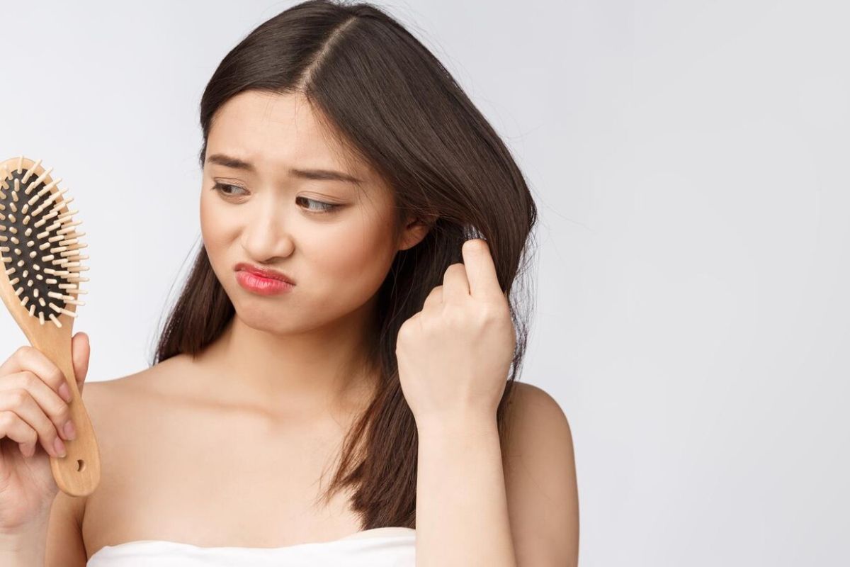 Wanita sedang memegang rambut dan sisir