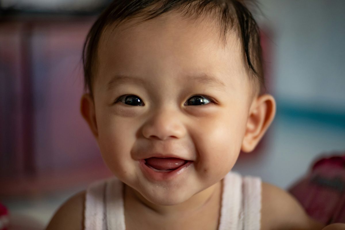 bayi yang sedang tersenyum ke arah kamera