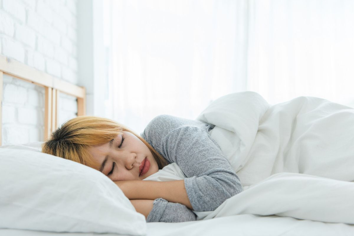 eorang wanita sedang beristirahat di atas tempat tidur