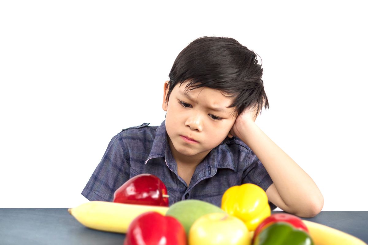 anak yang menatap bosan ke atas meja yang penuh buah