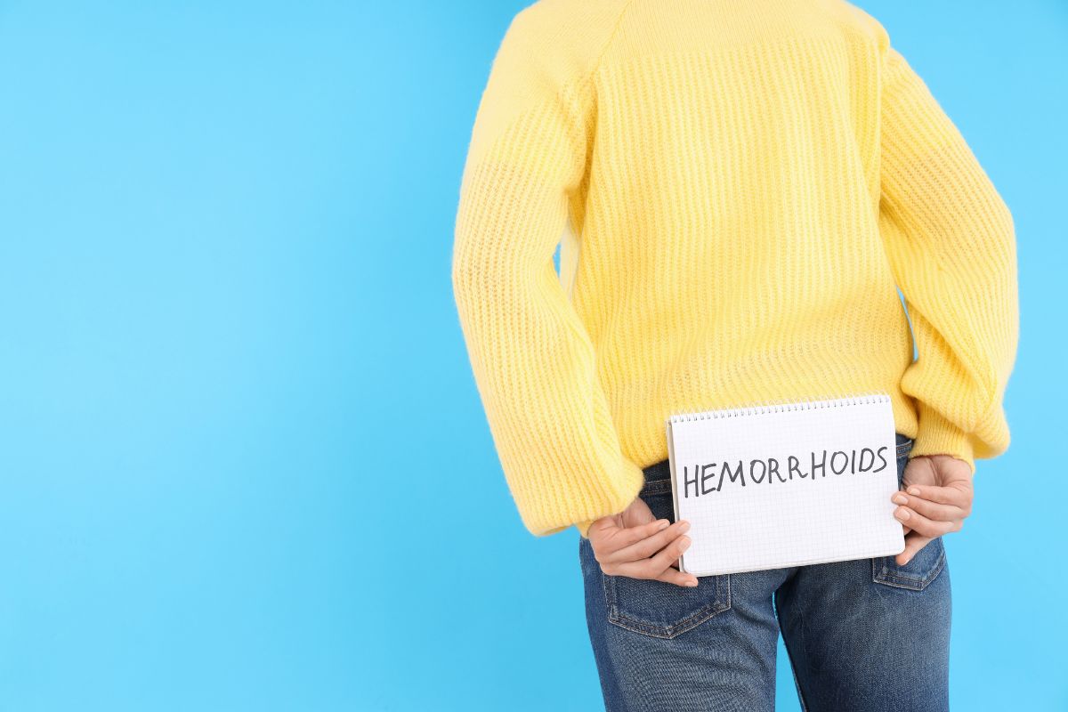 Pria yang sedang memegang kertas bertuliskan 'hemorrhoids'