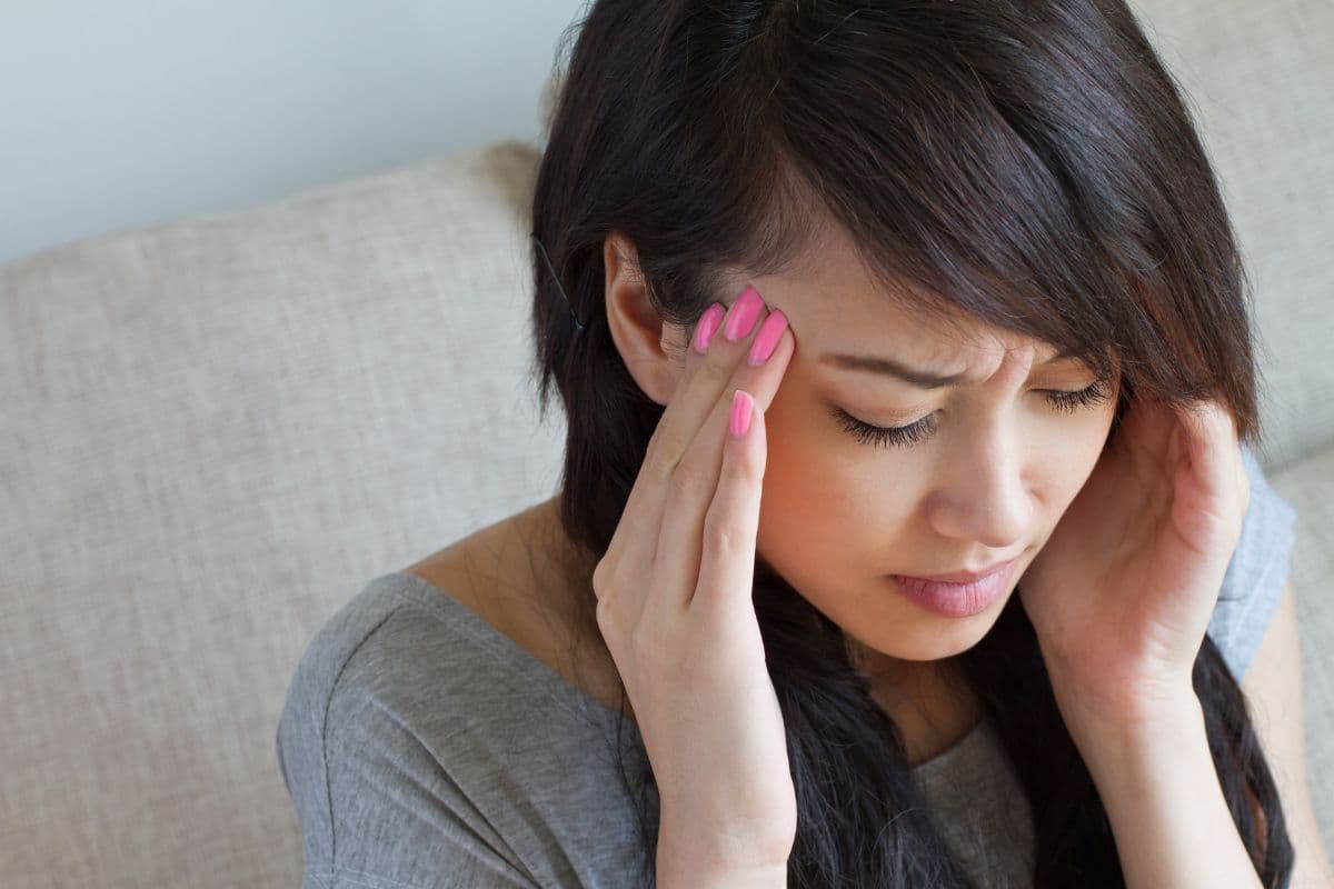 Wanita sedang memijat kepala yang pusing akibat vertigo