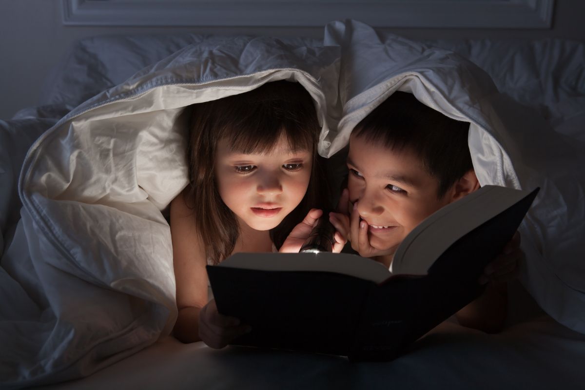 Dua anak yang sedang membaca dalam kondisi gelap