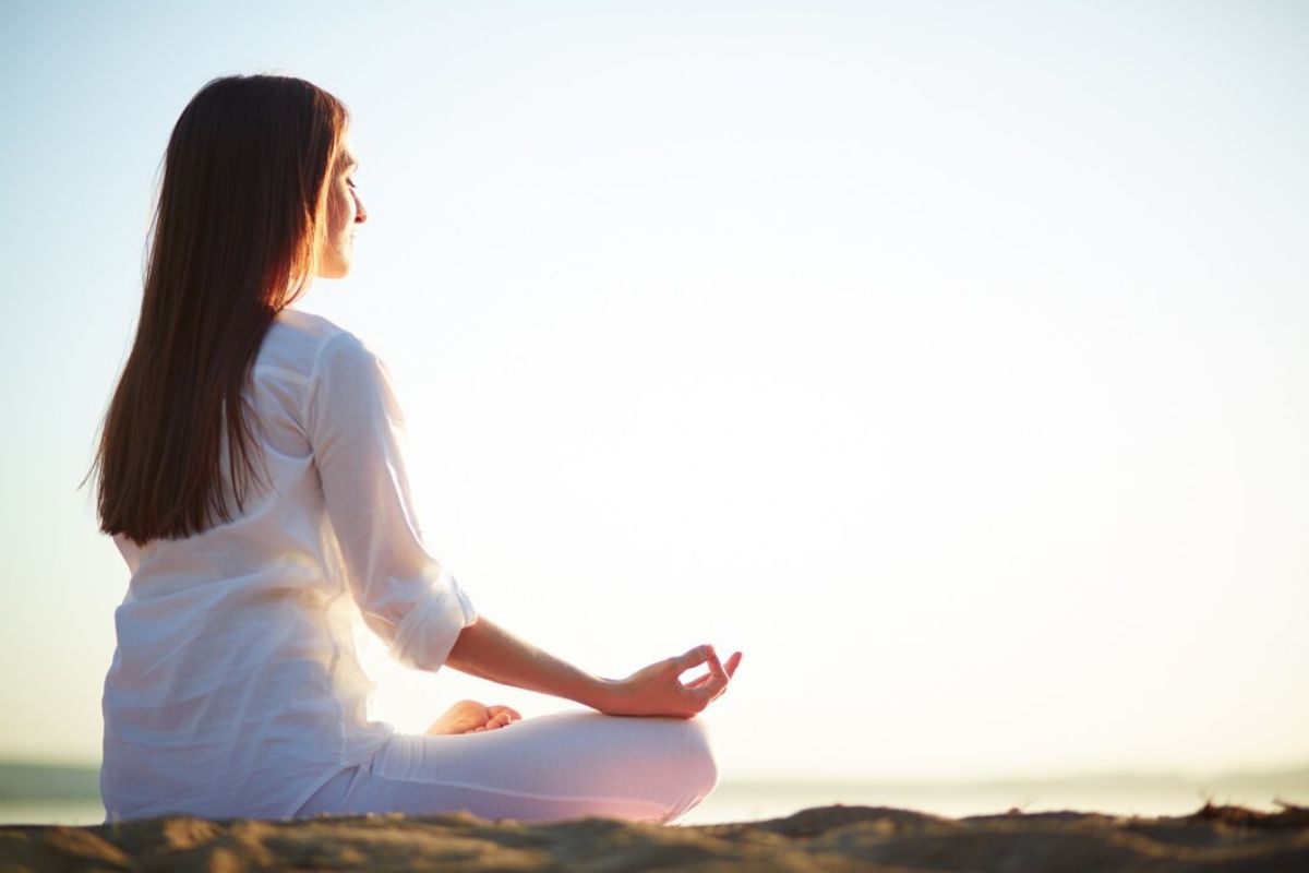 Perempuan meditasi di pinggir pantai