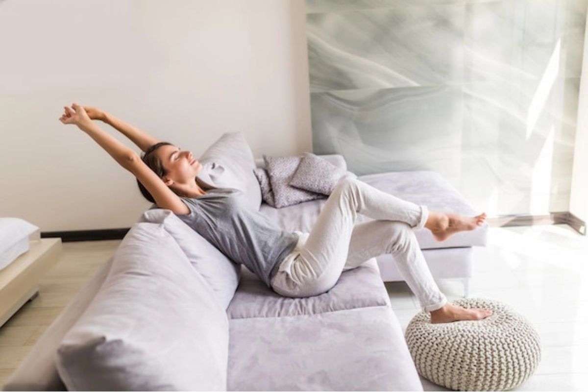 Perempuan tersenyum sedang melakukan stretching di sofa