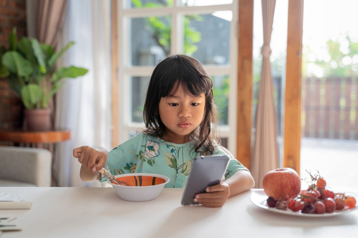 Anak makan sambil bermain ponsel