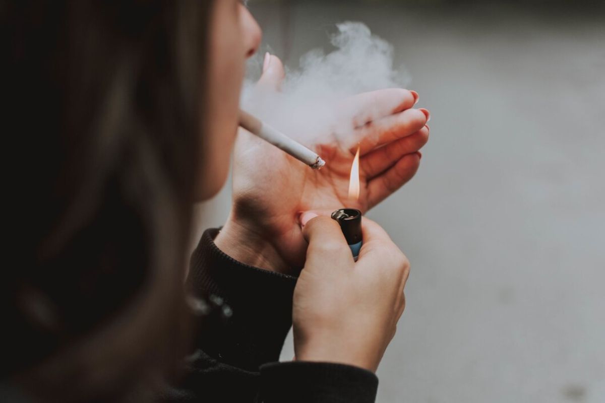 Perempuan menyalakan rokok