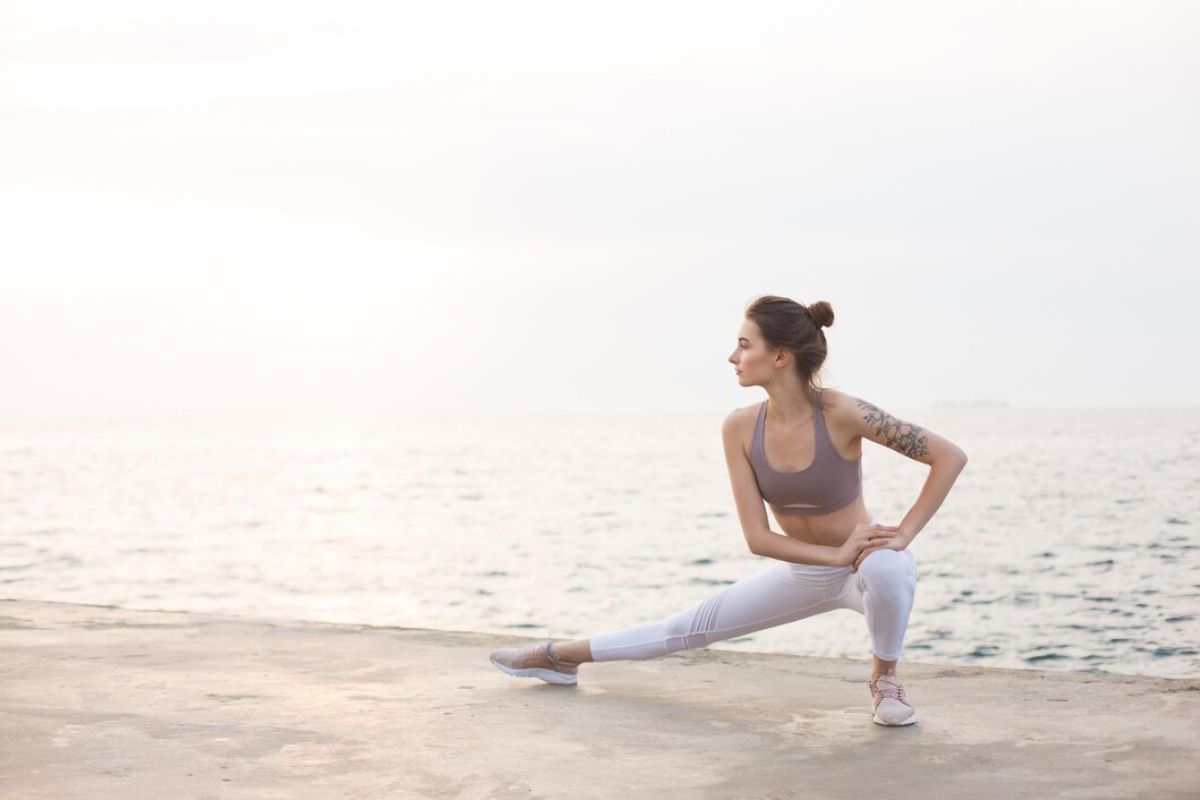 Perempuan stretching di pinggir pantai