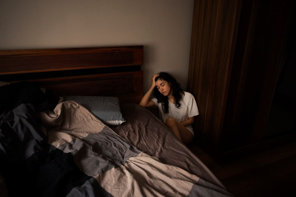 Perempuan duduk di sebelah tempat tidur