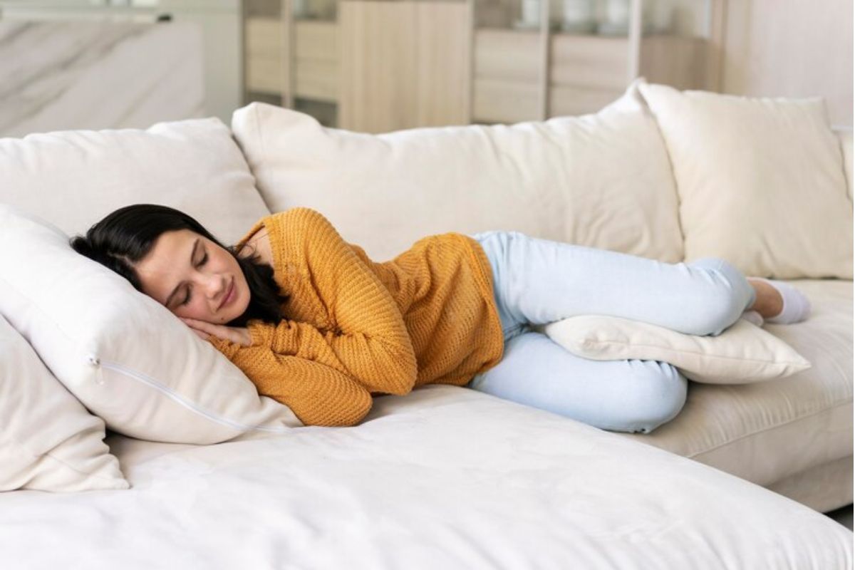 Seorang wanita sedang berbaring miring di sofa