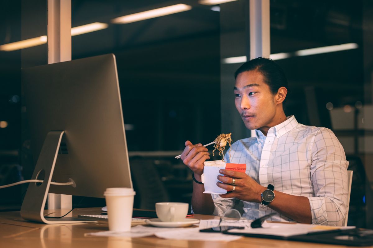 Pria sedang makan malam di depan komputer