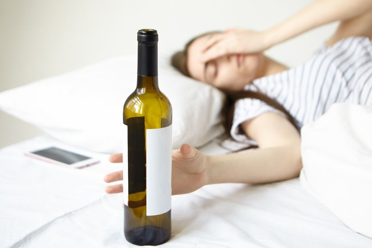 Perempuan memegang botol wine yang kosong