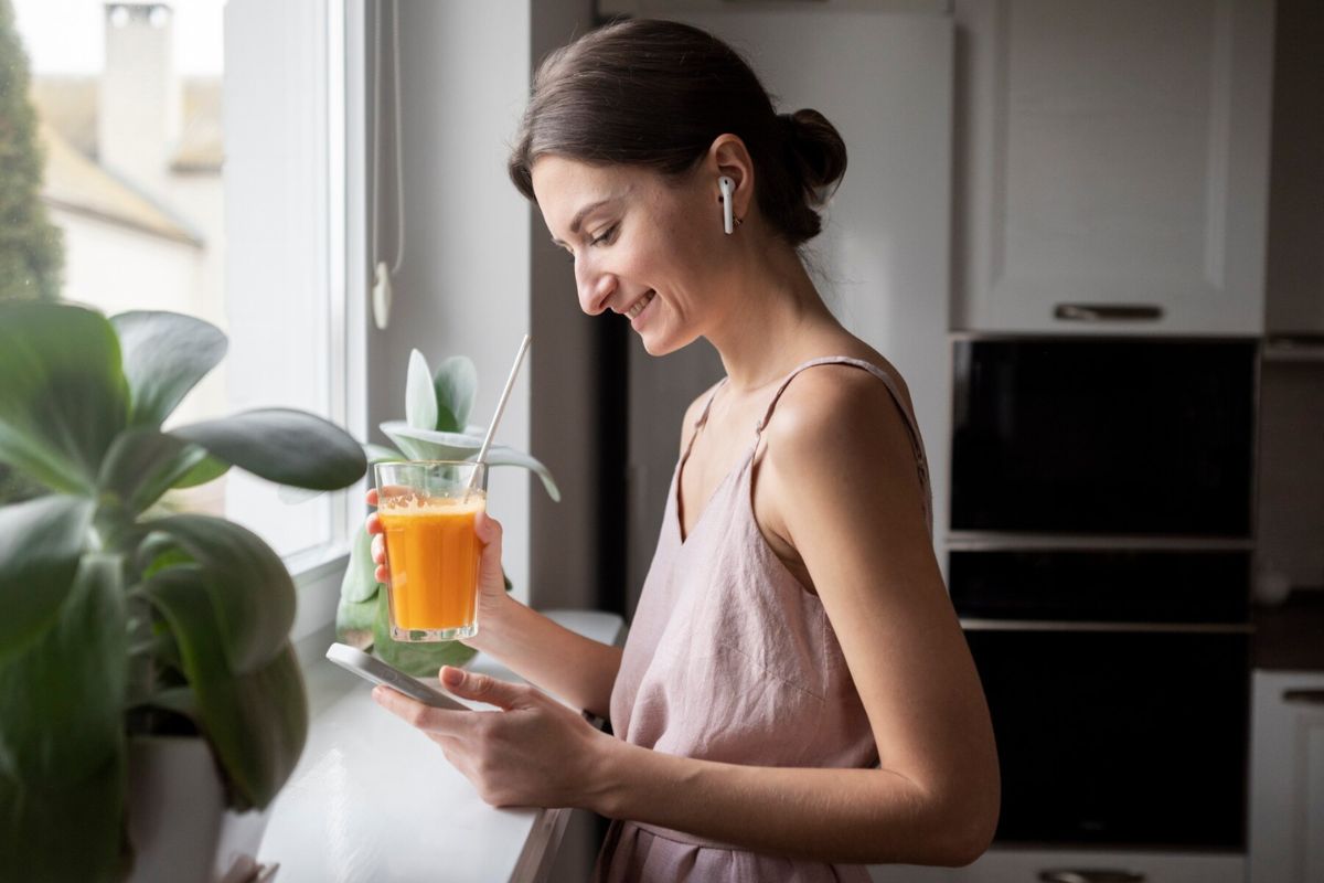 Seorang wanita memegang segelas jus jeruk yang kaya akan vitamin C