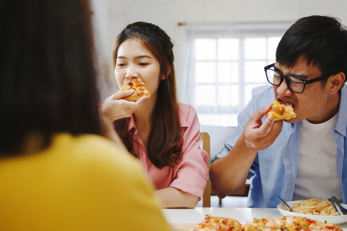 Pria dan wanita sedang makan pizza