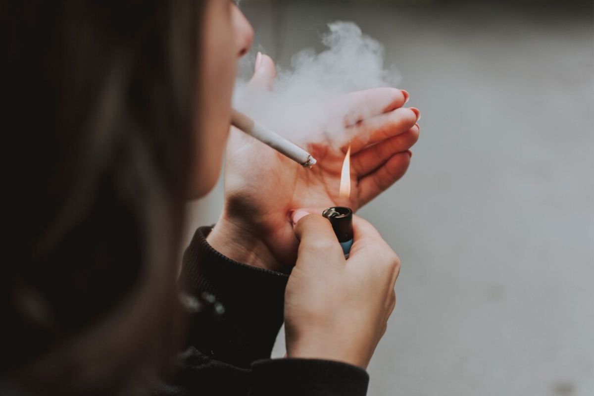 Perempuan menyalakan rokok