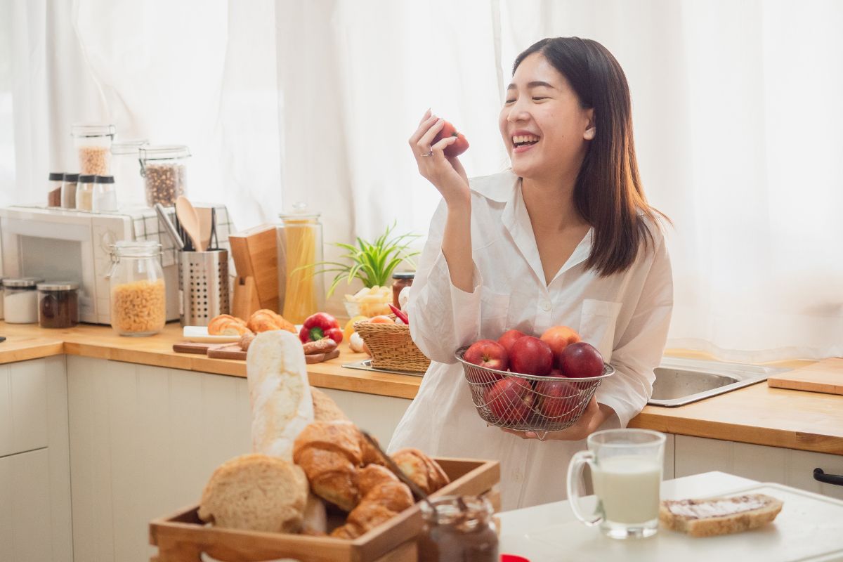 Seorang wanita sedang memakan buah apel merah